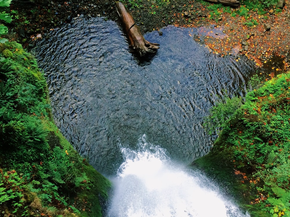 A top view of a waterfall tumbling down into a heart-shaped pond