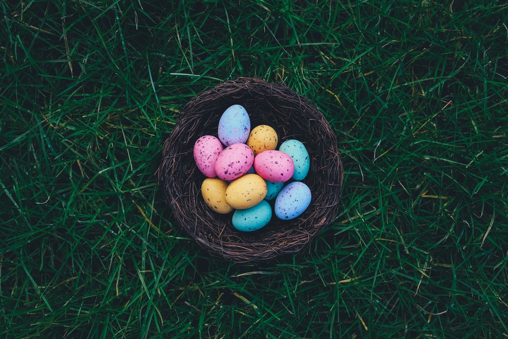 Multicolored speckled Easter eggs in a basket on grass