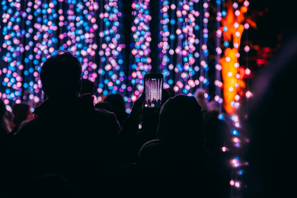 bokeh photography of person taking picture at stage
